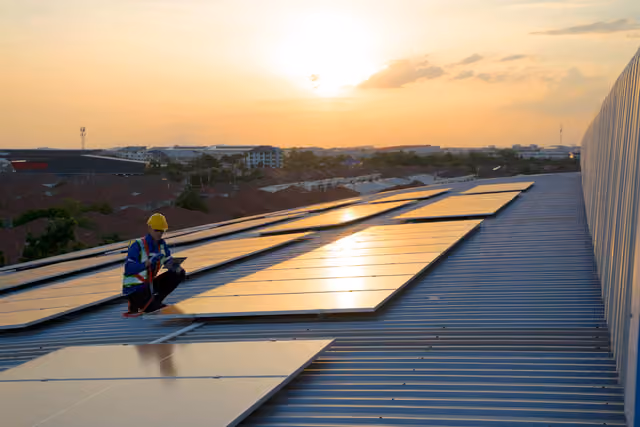 Installateur sur une toiture solaire au coucher du soleil